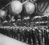 British barrage balloons are safely tucked away in their hangar for the night. WAAF balloon operators report for inspection before going off duty after a strenuous day of training.