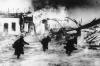 German soldiers move through a burning Norwegian village during the German invasion.