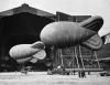 Barrage balloons outside a hangar at an airport.