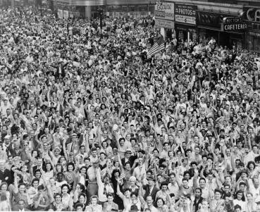 Crowd of people, many waving, in Times Square on V-J Day at time of announcement of the Japanese surrender.