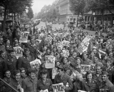 American servicemen and women gather in front of "Rainbow Corner" Red Cross club in Paris to celebrate the unconditional surrender of the Japanese.