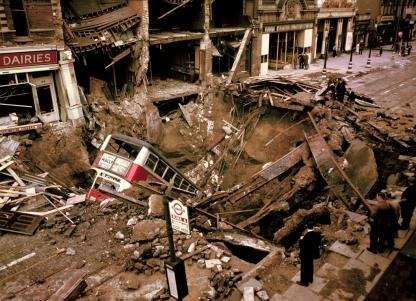 A London bus rests in a massive crater left by a German bomb.
