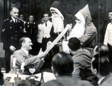 Fuhrer receives a present from two Santas while attending a Christmas party given by the Chief of the Chancellery.