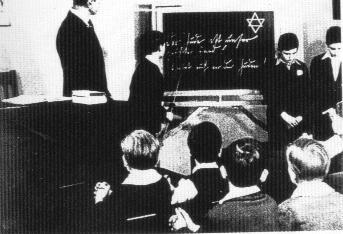 Jude student in front of the class. In the blackboard it's written: 'Jews are our enemy! Beware with jews!'